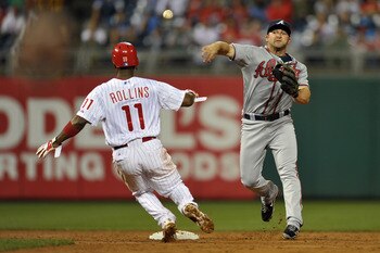 PHILADELPHIA, PA - JULY 08: Dan Uggla #26 of the Atlanta Braves throws to first base after forcing out Jimmy Rollins #11 of the Philadelphia Phillies at second at Citizens Bank Park on July 8, 2011 in Philadelphia, Pennsylvania.  The Phillies won 3-2 in t