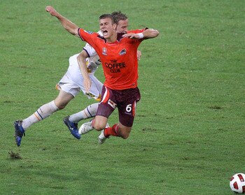 BRISBANE, AUSTRALIA - DECEMBER 26:  Erik Paartalu of the Roar is tackled in an illegal tacle by Michael Thwaite of the Gold Coast during the round 20 A-League match between the Brisbane Roar and Gold Coast United at Suncorp Stadium on December 26, 2010 in