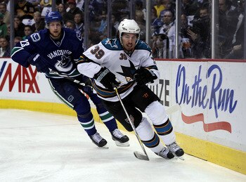 VANCOUVER, CANADA - MAY 24:  Alexander Edler #23 of the Vancouver Canucks and Logan Couture #39 of the San Jose Sharks skate behind the net in Game Five of the Western Conference Finals during the 2011 Stanley Cup Playoffs at Rogers Arena on May 24, 2011