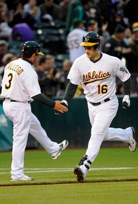 OAKLAND, CA - JULY 15: Josh Willingham #16 of the Oakland Athletics slaps the hand of third base coach Mike Gallego #3 after hitting a two-run home run against the Los Angeles Angels in the third inning during an MLB baseball game at the O.co Coliseum Jul