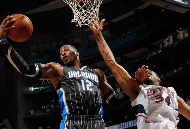 ATLANTA, GA - APRIL 24:  Dwight Howard #12 of the Orlando Magic grabs a rebound against Jason Collins #34 of the Atlanta Hawks during Game Four of the Eastern Conference Quarterfinals in the 2011 NBA Playoffs at Philips Arena on April 24, 2011 in Atlanta,