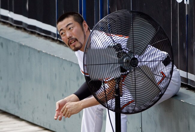 BALTIMORE, MD - JULY 17: Relief pitcher Koji Uehara #19 of the Baltimore Orioles sits in front of a fan while sitting in the bullpen during the sixth inning against the Cleveland Indians at Oriole Park at Camden Yards on July 17, 2011 in Baltimore, Maryla