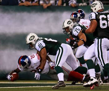 EAST RUTHERFORD, NJ - AUGUST 16:  Antrel Rolle #26 of the New York Giants is brought down by Dustin Keller #81 of the New York Jets near the endzone after making an interception and returning the ball 59 yards during their game at New Meadowlands Stadium