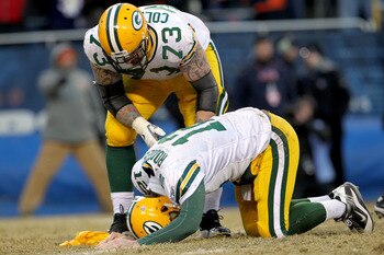 CHICAGO, IL - JANUARY 23:  Quarterback Aaron Rodgers #12 of the Green Bay Packers lays on the turf after getting hit by Julius Peppers #90 of the Chicago Bears in the helmet as Peppers was called for a personal foul in the fourth quarter of the NFC Champi