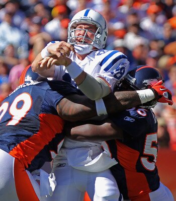 DENVER - SEPTEMBER 26:  Quarterback Peyton Manning #18 of the Indianapolis Colts gets rid of a pass as he is hit by defensive lineman Kevin Vickerson #99 and linebacker Robert Ayers #56 of the Denver Broncos at INVESCO Field at Mile High on September 26,