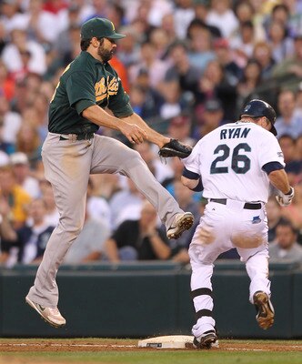 SEATTLE - AUGUST 02:  First baseman Conor Jackson #28 of the Oakland Athletics tries to tag out Brendan Ryan #26 of the Seattle Mariners on a high throw from starting pitcher Rich Harden at Safeco Field on August 2, 2011 in Seattle, Washington. Ryan was s