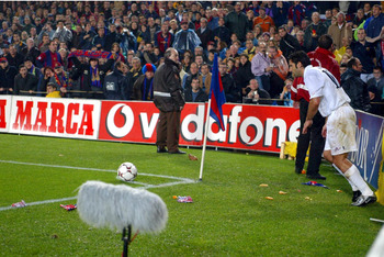BARCELONA - NOVEMBER 23: Luis Figo of Real Madrid is bombarded by missiles as he attempts to take a corner during the La Liga match between FC Barcelona and Real Madrid played at the Nou Camp Stadium, Barcelona, Spain on November 23, 2002. (Photo by Firo