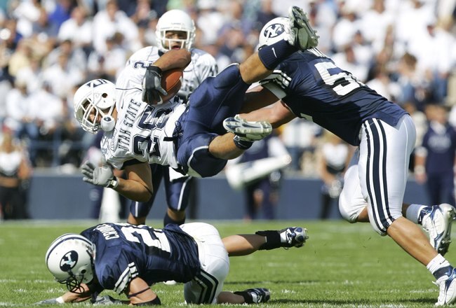 PROVO, UT - SEPTEMBER 23:   Lynwood Johnson #25 of Utah State is tackled by Ben Criddle #25 and Aaron Wagner #52 of BYU September 23, 2006 in Provo, Utah. BYU defeated Utah State 38-0.  (Photo by Kent Horner/Getty Images)