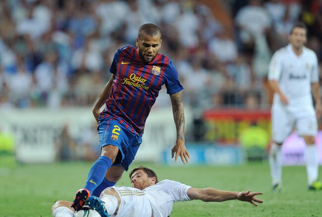 MADRID, SPAIN - AUGUST 14: Xabi Alonso (R) of Real Madrid tackles Dani Alves of Barcelona during the Super Cup first leg match between Real Madrid and Barcelona at Estadio Santiago Bernabeu on August 14, 2011 in Madrid, Spain.  (Photo by Denis Doyle/Getty