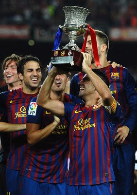 BARCELONA, SPAIN - AUGUST 17: Xavi and Cesc Fabregas of Barcelona celebrate with the trophy after victory in the Super Cup second leg match between Barcelona and Real Madrid at Nou Camp on August 17, 2011 in Barcelona, Spain.  (Photo by Laurence Griffiths