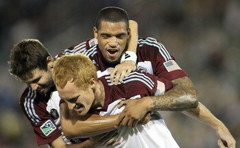 COMMERCE CITY, CO - AUGUST 20: Jeff Larentowicz #4 of the Colorado Rapids is mobbed by teammates Caleb Folan #21 and Drew Moor #3 after Larentowicz scored a goal against Chivas USA during their game at Dick's Sporting Goods Park August 20, 2011 in Commerc