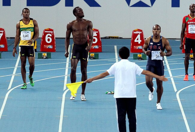 DAEGU, SOUTH KOREA - AUGUST 28:  An official flags in front of the runners as Usain Bolt (2nd L) of Jamaica reacts after false starting in the Men's 100 metre final during day two of 13th IAAF World Athletics Championships at the Daegu Stadium on August 2