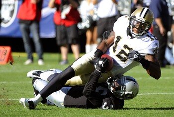 OAKLAND, CA - AUGUST 28:  Marques Colston #12 of the New Orleans Saints is dragged down at the one yard line by Tyvon Branch #33 of the Oakland Raiders in the first quarter during an NFL pre-season football game at the O.co Coliseum August 28, 2011 in Oak