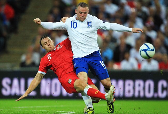 LONDON, ENGLAND - SEPTEMBER 06:  Wayne Rooney (R) of England is tackled by Darcy Blake (L) of Wales during the UEFA EURO 2012 group G qualifying match between England and Wales at Wembley Stadium  on September 6, 2011 in London, England.  (Photo by David 