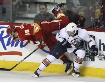 CALGARY, CANADA - APRIL 6: Tom Kostopoulos #16 of the Calgary Flames flies over Taylor Chorney #41 of the Edmonton Oilers in second period NHL action on April 6, 2011 at the Scotiabank Saddledome in Calgary, Alberta, Canada. (Photo by Mike Ridewood/Getty