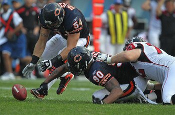 CHICAGO, IL - SEPTEMBER 11:  Brian Urlacher #54 of the Chicago Bears pics up a fumble that's out of the reach of teammate Julius Peppers #90 as Sam Baker #72 of the Atlanta Falcons holds back Peppers at Soldier Field on September 11, 2011 in Chicago, Illi