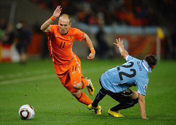 CAPE TOWN, SOUTH AFRICA - JULY 06:  Arjen Robben of the Netherlands evades the challenge of Martin Caceres of Uruguay during the 2010 FIFA World Cup South Africa Semi Final match between Uruguay and the Netherlands at Green Point Stadium on July 6, 2010 i