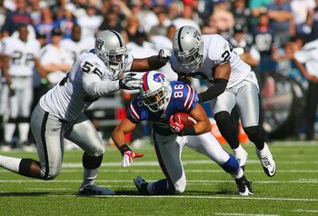 ORCHARD PARK, NY - SEPTEMBER 18:  David Nelson #86 of the Buffalo Bills dives forward for a first down as Rolando McClain #55 and Michael Huff #24 of the Oakland Raiders tackle him at Ralph Wilson Stadium on September 18, 2011 in Orchard Park, New York. B