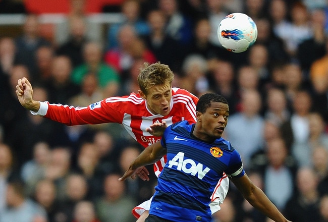 STOKE ON TRENT, ENGLAND - SEPTEMBER 24:  Peter Crouch of Stoke City and Patrice Evra of Manchester United jump in the air for the ball during the Barclays Premier League match between Stoke City and Manchester United at the Britannia Stadium on September