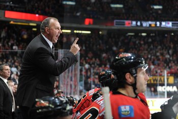 Brent Sutter pointing his finger at something. Possibly the scoreboard.