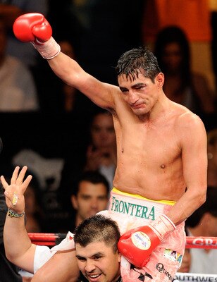 Erik Morales held high in celebrating his junior welterweight world championship victory.