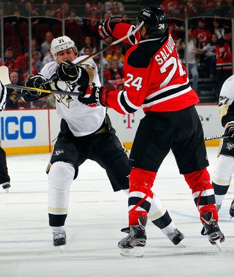 NEWARK, NJ - DECEMBER 31:  Evgeni Malkin #71 of the Pittsburgh Penguins gets his stick up high as he is hit by Bryce Salvador #24 of the New Jersey Devils in the first period of an NHL hockey game at Prudential Center on December 31, 2011 in Newark, New J