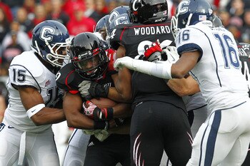 CINCINNATI, OH - DECEMBER 03:  Ralph David Abernathy IV #19 of the Cincinnati Bearcats is tackled by Jerome Junior #15 of the Connecticut Huskies on December 3, 2011 at Nippert Stadium in Cincinnati, Ohio. Cincinnati defeated Connecticut 35-27. (Photo by 