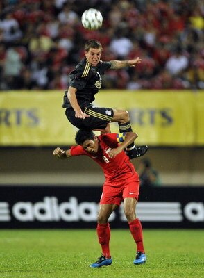 SINGAPORE - JULY 26:  SINGAPORE- JULY 26:  Daniel Agger of Liverpool jumps for the ball over Noh Alam Sham of Singapore during the pre-season friendly soccer match between Singapore and Liverpool at the National Stadium, July 26, 2009 in Singapore.  (Phot