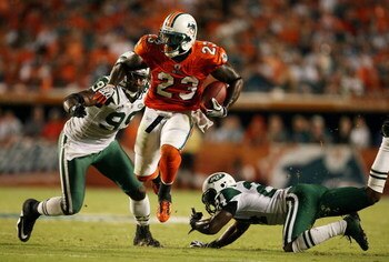MIAMI - OCTOBER 12:  Running back Ronnie Brown #23 of the Miami Dolphins jumps between linebacker Bryan Thomas #99 and cornerback Darrelle Revis #24 of the New York Jets at Land Shark Stadium on October 12, 2009 in Miami, Florida. The Dolphins defeated th