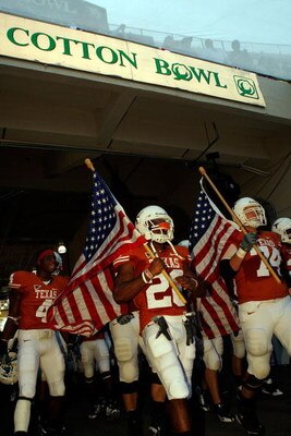 DALLAS - OCTOBER 17:  Running back Fozzy Whittaker #28 and Adam Ulatoski #74 of the Texas Longhorns carry American flags as the walk to the field before a game against the Oklahoma Sooners at Cotton Bowl on October 17, 2009 in Dallas, Texas.  (Photo by Ro