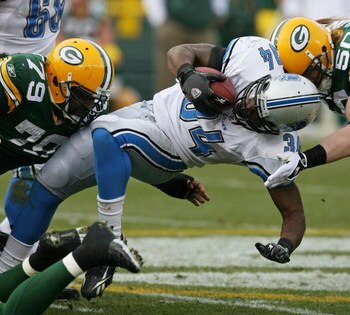 GREEN BAY, WI - OCTOBER 18:  Kevin Smith #34 of the Detroit Lions is tackled by Ryan Pickett #79 and A.J. Hawk #50 of the Green Bay Packers at Lambeau Field on October 18, 2009 in Green Bay, Wisconsin. The Packers defeated the Lions 26-0. (Photo by Jonath