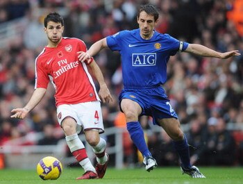 LONDON - NOVEMBER 08:   Francesc Fabregas of Arsenal holds off Gary Neville of Manchester United as he passes to Samir Nasri to score their second goal during the Barclays Premier League match between Arsenal and Manchester United at the Emirates Stadium 