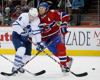 MONTREAL- JANUARY 8:  Mike Komisarek #8 of the Montreal Canadiens body checks Matt Stajan #14 of the Toronto Maple Leafs at the Bell Centre on January 08, 2009 in Montreal, Quebec, Canada.   The Montreal Canadiens defeated the Toronto Maple Leafs 6-2.  (P