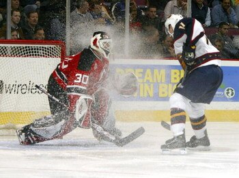 EAST RUTHERFORD, NJ - DECEMBER 19:  Goaltender Martin Broduer #30 of the New Jersey Devils  has ice kicked up into his face by J.P. Vigier #11 of the Atlanta Thrashers on December 19, 2006 at the Continental Airlines Arena in East Rutherford, New Jersey. 