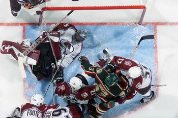 DENVER - APRIL 12:  Goalie Patrick Roy #33 of the Colorado Avalanche stops the puck between his legs as Sergei Zholtok #33 of the Minnesota Wild gets caught in the crease between Mike Keane #12 and Derek Morris #53 during the first round of the 2003 Stanl