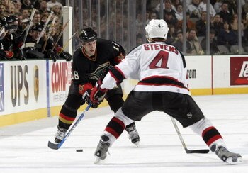 DALLAS - NOVEMBER 28:  Right wing RobDiMaio #18 of the Dallas Stars moves the puck as he is covered by defenseman Scott Stevens #4 of the New Jersey Devils during the game at the American Airlines Center on November 28, 2003 in Dallas, Texas. The Stars de