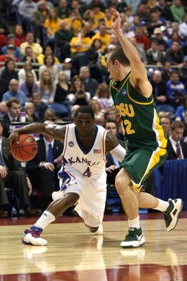 MINNEAPOLIS - MARCH 20:  Sherron Collins #4 of the Kansas Jayhawks drives the ball in the second half against Josh Vaughn #32 of the North Dakota State Bison during the first round of the NCAA Division I Men's Basketball Tournament at the Hubert H. Humphr