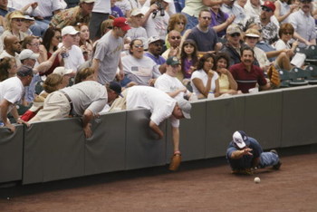 DENVER - MAY 19:  A fan finds himself in a bit of a predicament after falling over the wall in an attempt to snag a foul ball at Coors Field in Denver, Colorado, on May 19, 2002.  The Colorado Rockies fell to the Atlanta Braves 2-1.   (Photo by Brian Bahr