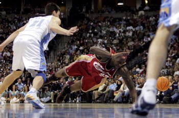 DENVER - JANUARY 19:  LeBron James #23 of the Cleveland Cavaliers looses the ball as he trips while driving past Eduardo Najera #21 of the Denver Nuggets as James notched a triple double in a loosing effort as the Nuggets defeated the Cavaliers 110-99 dur