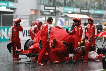 KUALA LUMPUR, MALAYSIA - APRIL 05:  Ferrari mechanics shelter their car during heavy rain during the Malaysian Formula One Grand Prix at the Sepang Circuit on April 5, 2009 in Kuala Lumpur, Malaysia.  (Photo by Paul Gilham/Getty Images)