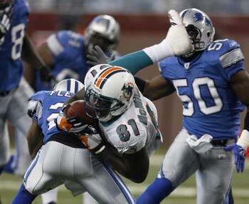 DETROIT - NOVEMBER 23:  Randy McMichael #81 of the Miami Dolphins is taken off his feat after a second quarter catch by Jamar Fletcher #21 of the Detroit Lions in front of Ernie Sims #50 on November 23, 2006 at Ford Field in Detroit, Michigan. (Photo By G