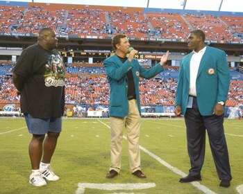 Former  Miami Dolphins  quarterback Dan Marino and offensive lineman Keith Simms (left) honor lineman Richmond Webb, who retired, August 21, 2004 in Miami.  (Photo by Al Messerschmidt/Getty Images)