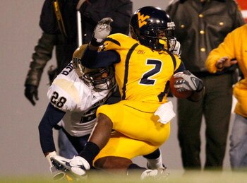 MORGANTOWN, WV - DECEMBER 1:  Defensive back Eric Thatcher # 28 of the Pittsburgh Panthers tackles receiver Darius Reynaud #2 of the West Virginia Mountaineers during the first half at Milan Puskar Stadium December 1, 2007 in Morgantown, West Virginia.  P