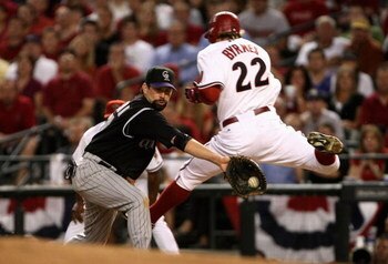 PHOENIX - OCTOBER 11:  Eric Byrnes #22 of the Arizona Diamondbacks leaps past Todd Helton #17 of the Colorado Rockies for an infield single during the sixth inning of Game One of the National League Championship Series at Chase Field on October 11, 2007 i