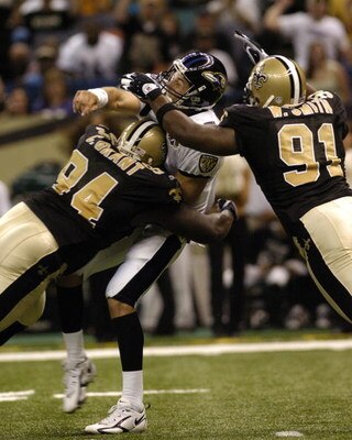 New Orleans Saints defenders Charles Grant (94) and Will Smith (91) hit Baltimore Ravens quarterback Kyle Boller   in the first half of a pre-season game against the Baltimore Ravens August 26, 2005 in New Orleans.  (Photo by Al Messerschmidt/Getty Images