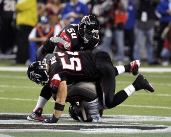 ATLANTA - DECEMBER 14: Running back Warrick Dunn #28 of the Tampa Bay Buccaneers tumbles under the tackle of linebackers Curtis Lofton #50 and Coy Wire #52 of the Atlanta Falcons at the Georgia Dome on December 14, 2008 in Atlanta, Georgia.  (Photo by Al 
