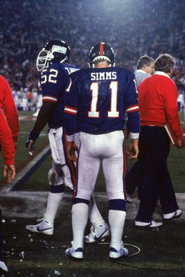 PASADENA, CA - JANUARY 25:  Quarterback Phil Simms #11 of the New York Giants stands on the sideline against the Denver Broncos during Super Bowl XXI at the Rose Bowl on January 25, 1987 in Pasadena, California. The Giants defeated the Broncos 39-20. (Pho