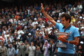 PARIS - JUNE 07:   Roger Federer of Switzerland salutes the fans as he holds the trophy following victory during the Men's Singles Final match against Robin Soderling of Sweden on day fifteen of the French Open at Roland Garros on June 7, 2009 in Paris, F