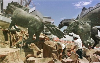 392092 03: Construction workers put the finishing touches on a sculpture of seven galloping bronze horses July 18, 2001 at Invesco Field in Denver, CO. The seven galloping bronze horses by Italian artist Sergio Benvenuti weighing 2 to 3 tons were commissi