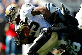 CHARLOTTE, NC - OCTOBER 19:  Running back Reggie Bush #25 of the New Orleans Saints is tackled by Na'il Diggs #53 and Tyler Brayton #96 of the Carolina Panthers during the game at Bank of America Stadium on October 19, 2008 in Charlotte, North Carolina.  